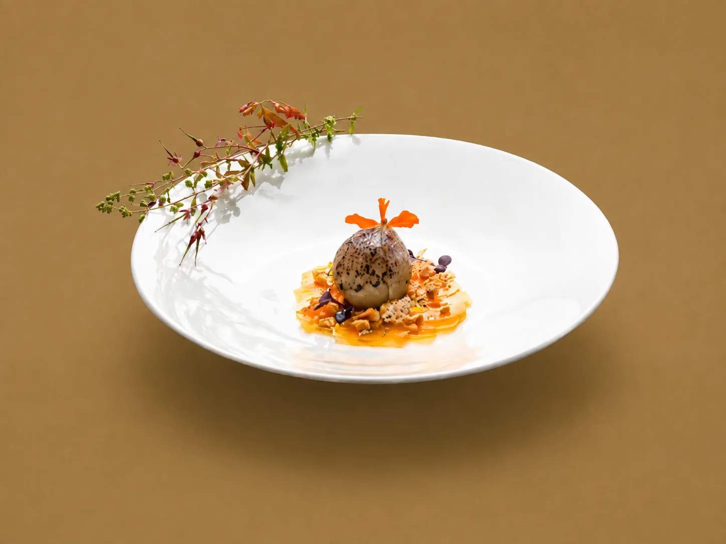 Bouchée sombre entourée de fleurs et de légumes orangés dans une assiette blanche