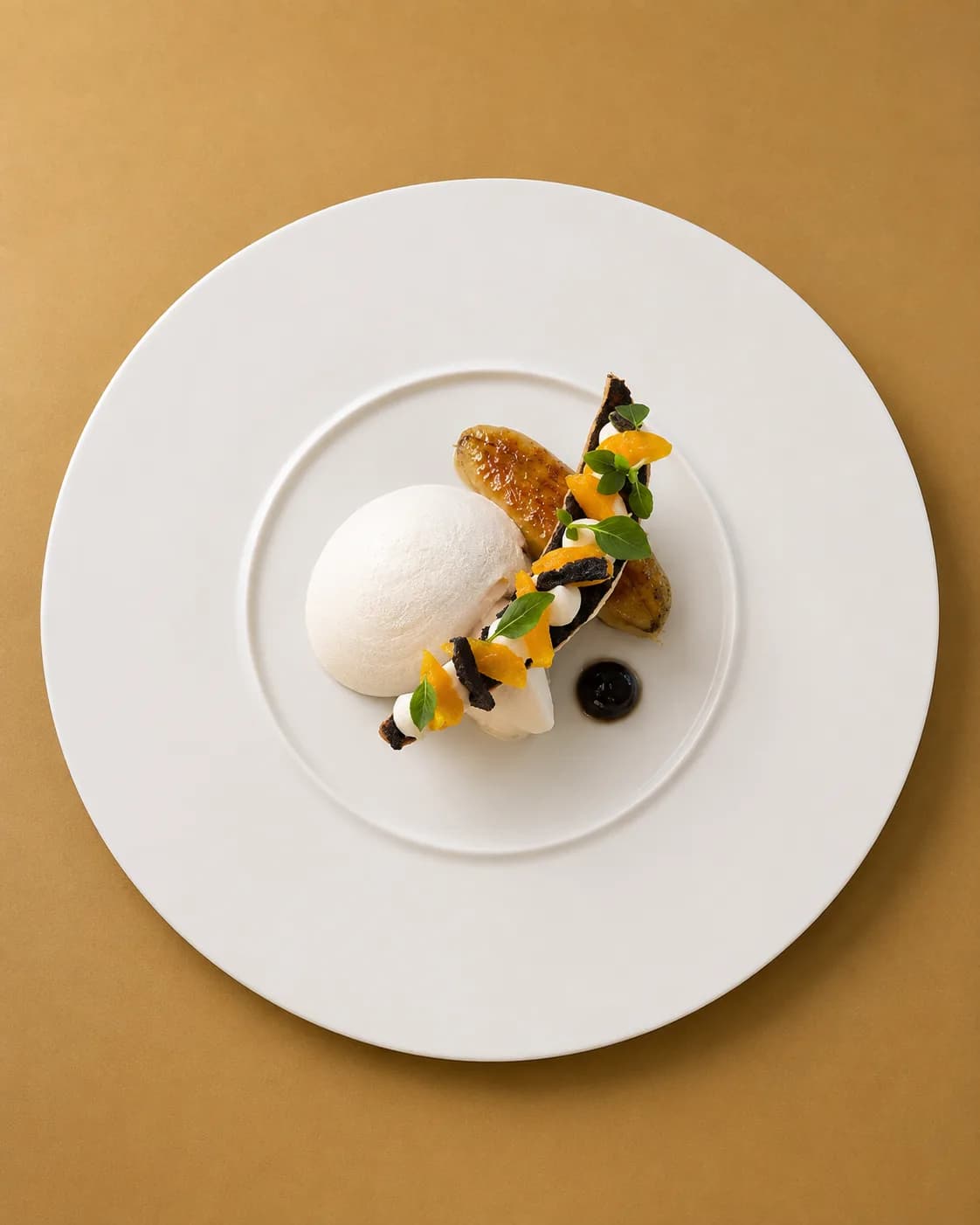 Banane rôtie et quenelle de glace blanche, suprêmes d'orange, éclats sombres et pousses de basilic