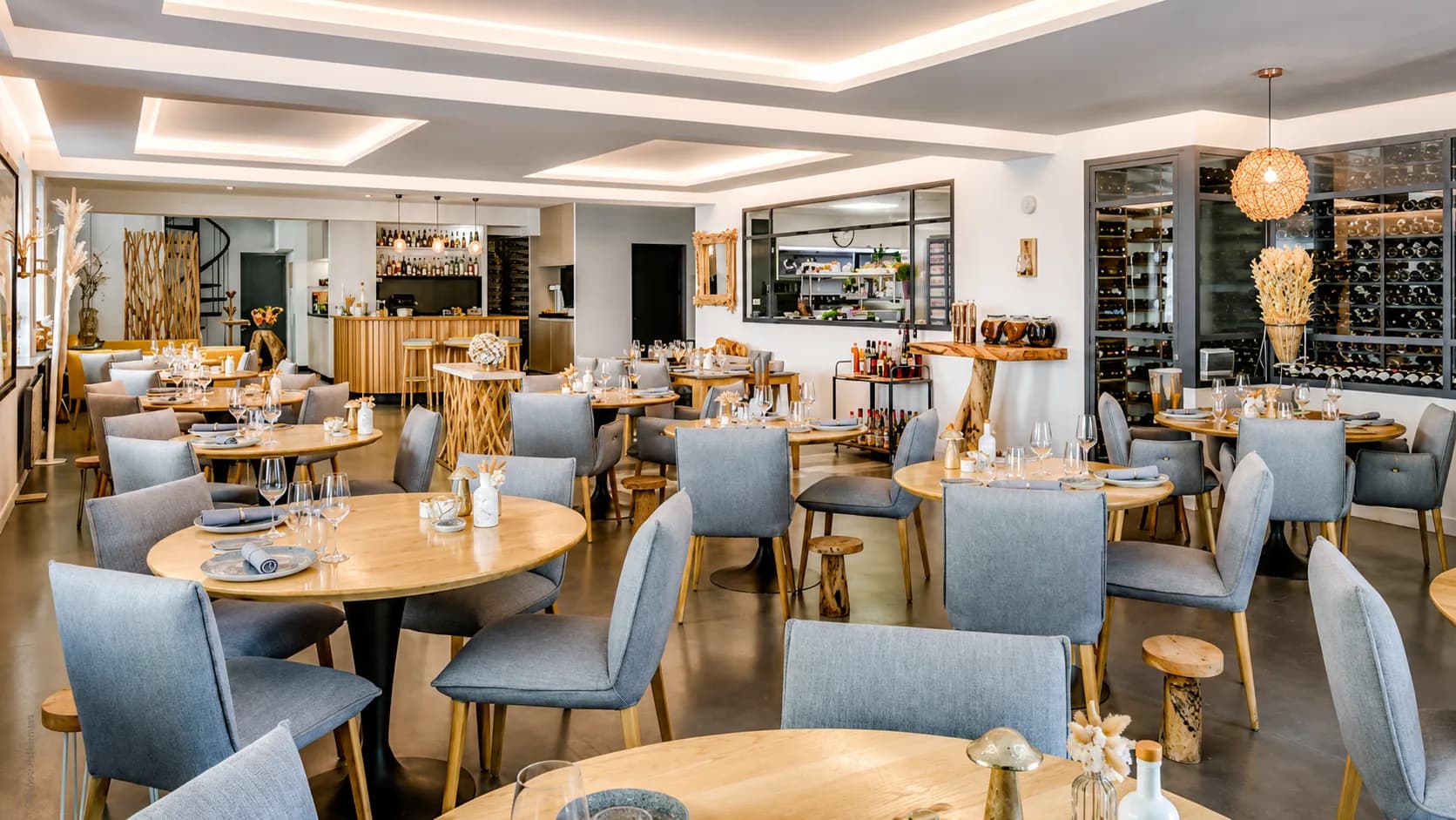 Salle de L'Or Q'idée avec la cave vitrée et la cuisine en arrière-plan