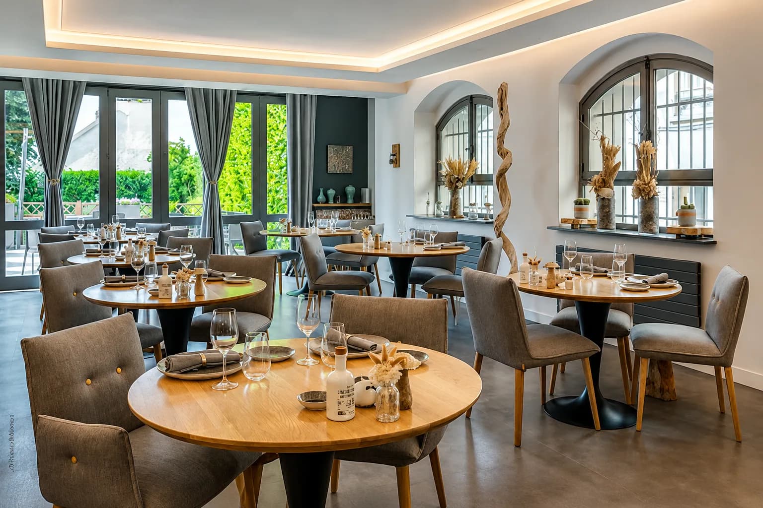 Tables rondes de la salle baignées par les grandes fenêtres