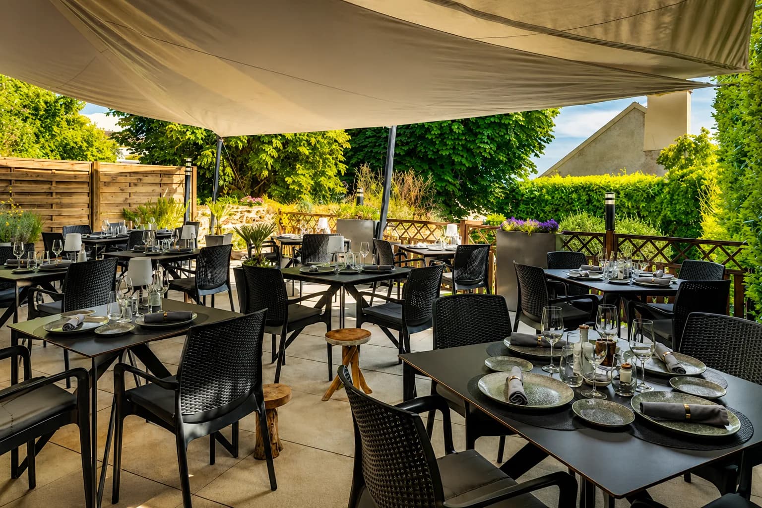 Grande terrasse dressée sous une toile entourée de verdure